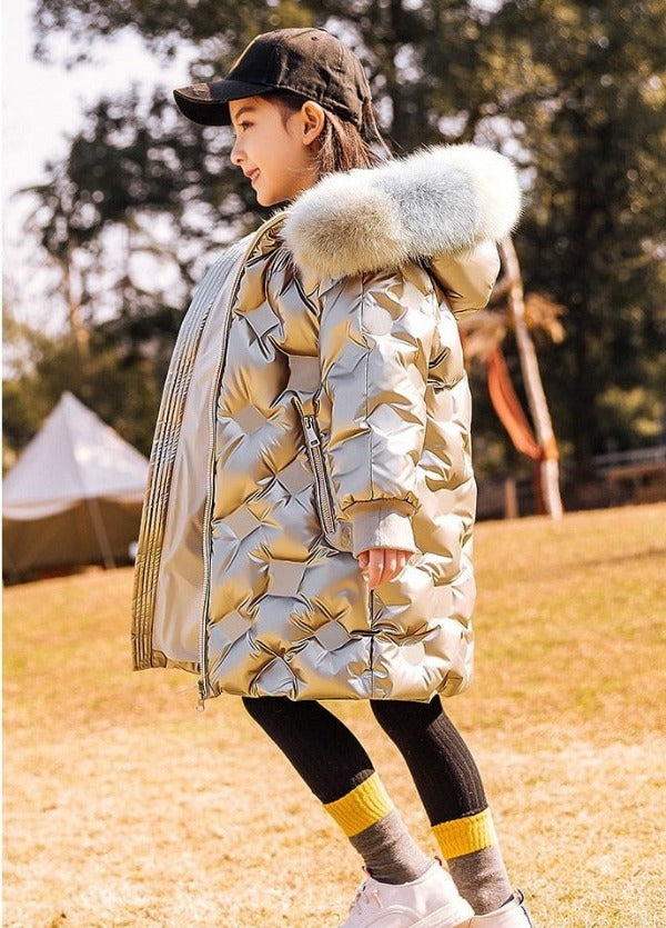 side view of a cute 8 year old girl wearing our knee-length quilted coat color silver metallic
