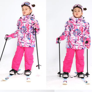 a happy girl wearing a pink ski parka and pants set