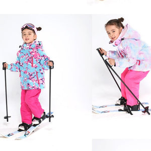 a happy 5 year old girl going skiing wearing her pink ski jacket and pants set
