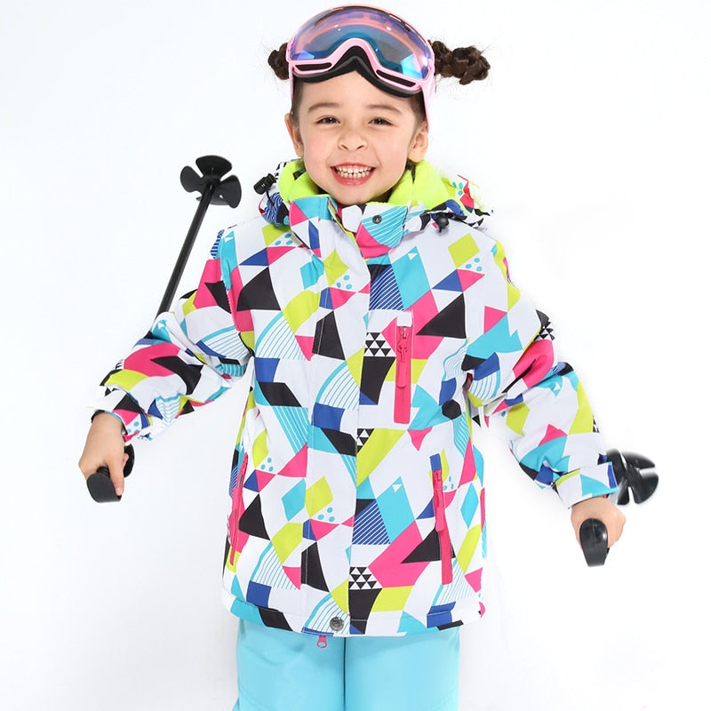 a happy 6 year old girl wearing a ski jacket and pants set