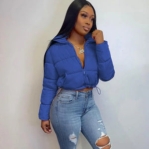 a gorgeous young black  skinned woman wearing a denim blue cropped puffer jacket standing at a white background