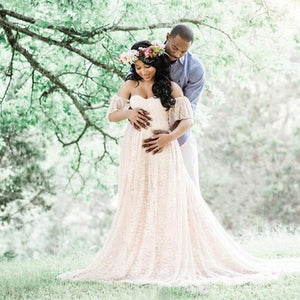 a happy couple posing for a pregnancy fotoshoot. the woman is wearing a cute lace dress