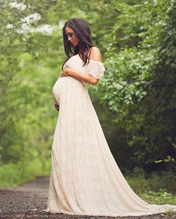 side view of a beautiful pregnant woman wearing a pregnancy photoshoot dress with open shoulders, sweet-heart neckline, elasticesed waist and long trail