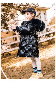 a cute 6 year old girl wearing knee long quilted coat color black with metallic shine is playing with her toy bunny